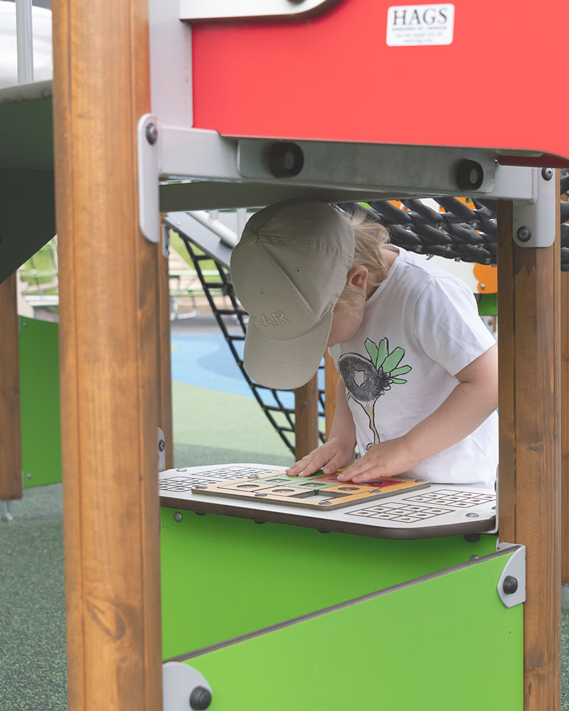 Ein kleines Kind ist auf einem Spielplatz mit einer Spieltafel tief in sich versunken.